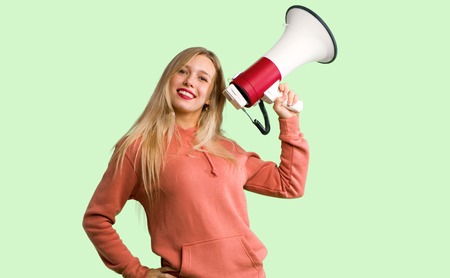 Young girl holding a megaphone on green backgroundの写真素材