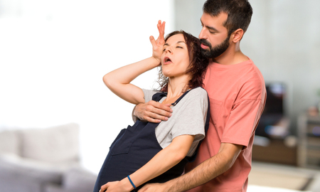 Couple with pregnant woman fainting of childbirth inside houseの写真素材