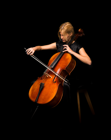 Young girl playing the cello on isolated black backgroundの写真素材