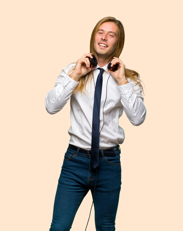 Blond businessman with long hair with headphones on isolated backgroundの写真素材
