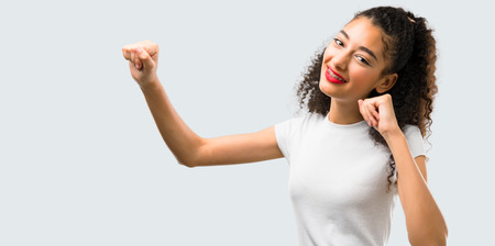 Young girl with curly hair celebrating a victory and surprised to be successful on grey backgroundの写真素材