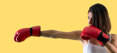 Sport woman with boxing gloves on yellow backgroundの写真素材