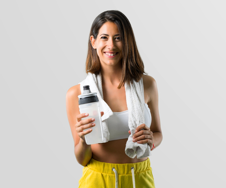 Sport woman with a bottle and towel on grey backgroundの写真素材