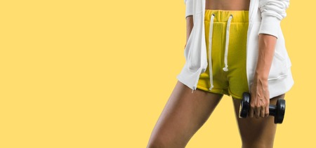 Sport woman making weightlifting on yellow backgroundの写真素材