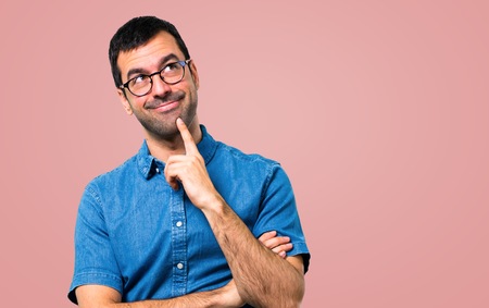Handsome man with blue shirt and glasses on pink backgroundの写真素材