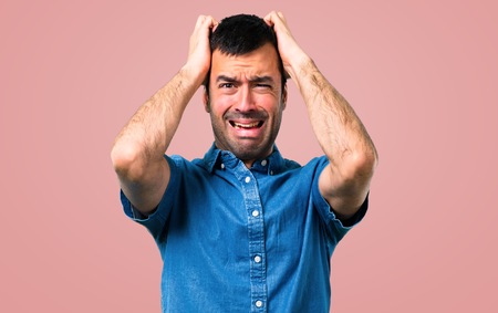 Handsome man with blue shirt unhappy and frustrated with something. Negative facial expression on pink backgroundの写真素材