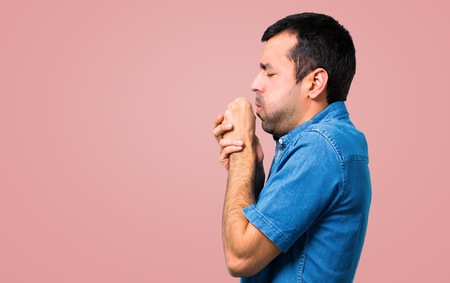 Handsome man with blue shirt is suffering with cough and feeling bad on pink backgroundの写真素材