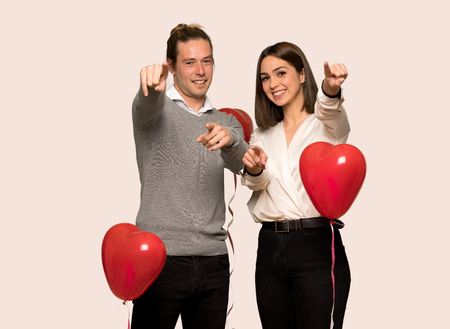 Couple in valentine day points finger at you while smiling over isolated backgroundの写真素材