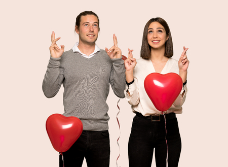 Couple in valentine day with fingers crossing and wishing the best over isolated backgroundの写真素材