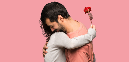 Couple in valentine day with flowers over isolated pink backgroundの写真素材
