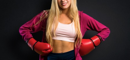 Pretty sport woman with boxing gloves on textured black backgroundの写真素材
