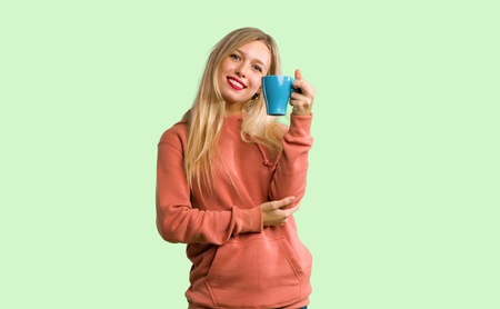Young girl holding a hot cup of coffee on green backgroundの写真素材