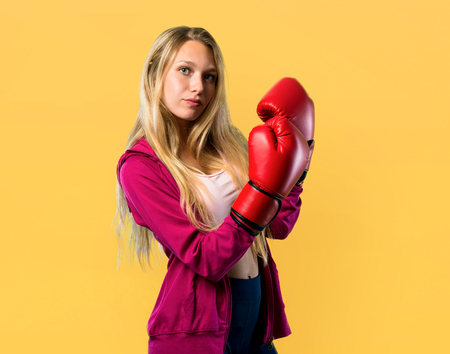 Pretty sport woman with boxing gloves on yellow backgroundの写真素材