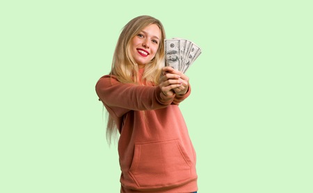 Young girl taking a lot of money on green backgroundの写真素材