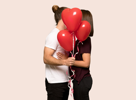 Couple in valentine day with balloons with heart shape over isolated backgroundの写真素材