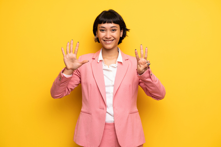 Modern woman with pink business suit counting eight with fingersの写真素材