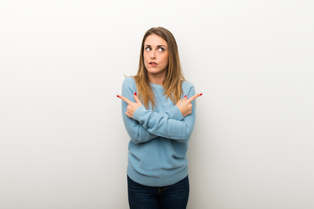 Blonde woman on isolated white background pointing to the laterals having doubtsの写真素材