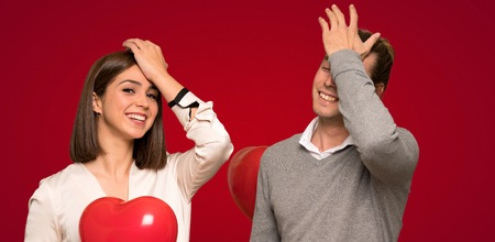 Couple in valentine day has just realized something and has intending the solution over red backgroundの写真素材