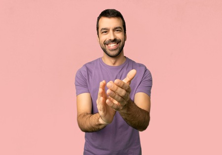 Handsome man applauding after presentation in a conference on isolated pink background