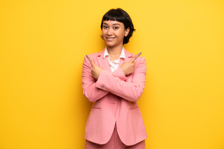 Modern woman with pink business suit pointing to the laterals having doubtsの写真素材