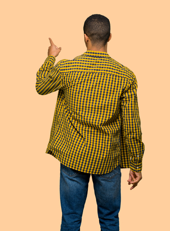 Young afro american man pointing back with the index finger on isolated backgroundの写真素材