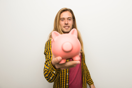 Blond man with long hair and with checkered shirt holding a piggybankの写真素材