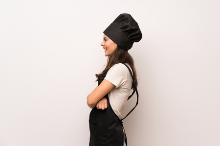 Teenager chef  over white wall in lateral position