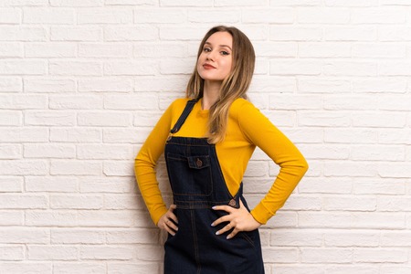 Teenager girl over white brick wall posing with arms at hip and smilingの写真素材