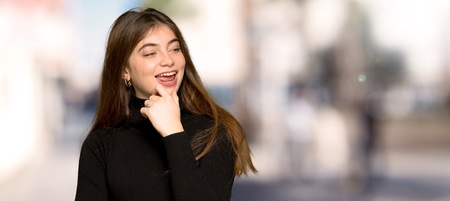Pretty girl looking to the side with the hand on the chin at outdoorsの写真素材