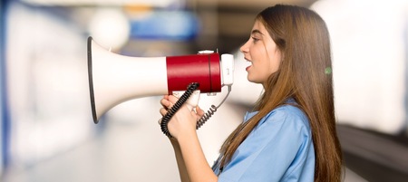 Young nurse shouting through a megaphone in a hospitalの写真素材