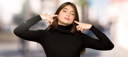 Pretty girl covering both ears with hands at outdoorsの写真素材