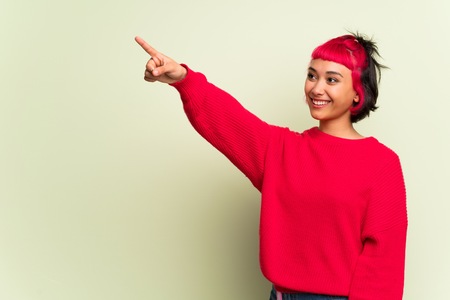 Young woman with red sweater pointing awayの写真素材