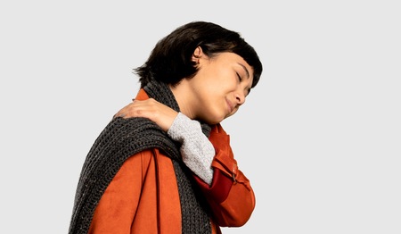 Short hair woman with coat suffering from pain in shoulder for having made an effort on isolated grey backgroundの写真素材