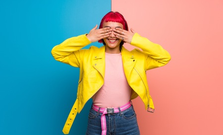 Young woman with yellow jacket covering eyes by hands. Surprised to see what is aheadの写真素材