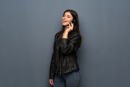 Teenager girl over grey wall keeping a conversation with the mobile phoneの写真素材