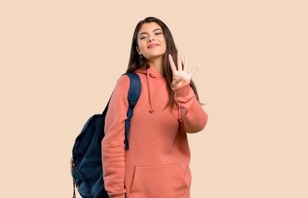 Teenager girl with sweatshirt and backpack happy and counting four with fingers on color backgroundの写真素材
