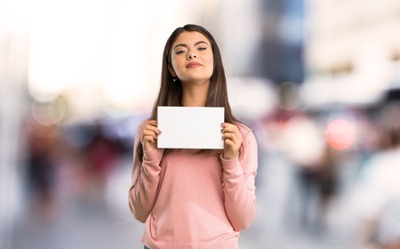 Teenager girl with pink shirt holding a placard for insert a concept at cityの写真素材