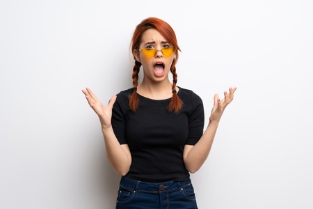 Young redhead woman over white wall frustrated by a bad situationの写真素材