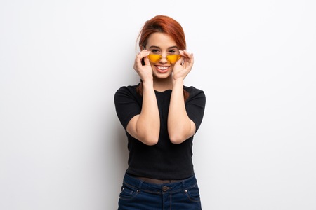 Young redhead woman over white wall with glasses and surprised