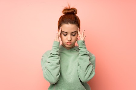 Young redhead woman with sweatshirt with headacheの写真素材