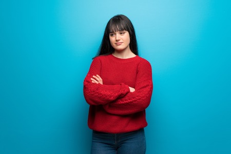 Woman with red sweater over blue wall portraitの写真素材