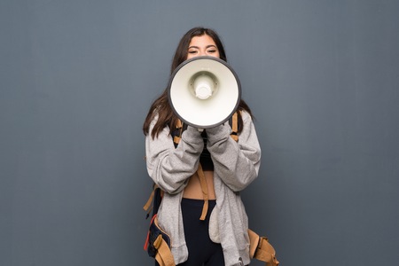Teenager traveler girl over wall shouting through a megaphoneの写真素材