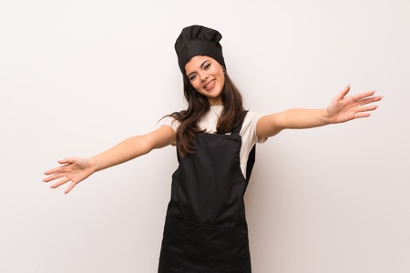 Teenager chef  over white wall presenting and inviting to come with handの写真素材