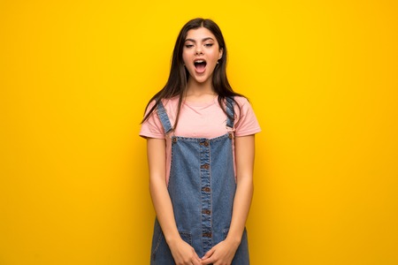 Teenager girl over yellow wall with surprise facial expressionの写真素材