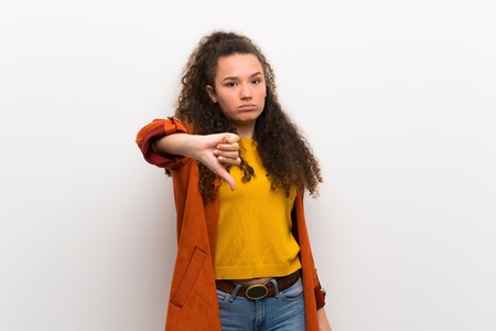 Teenager girl with coat showing thumb down with negative expressionの写真素材