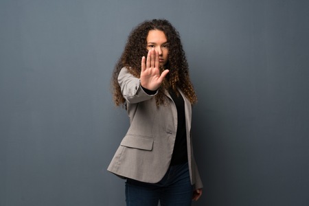 Teenager girl over blue wall making stop gesture denying a situation that thinks wrongの写真素材
