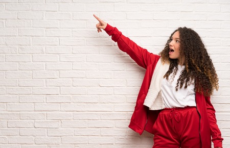 Teenager sport girl with curly hair pointing awayの写真素材