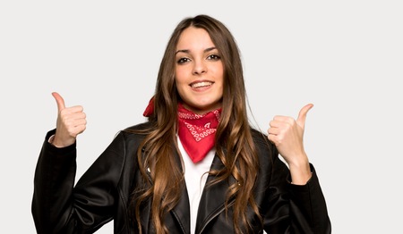 Young woman with leather jacket giving a thumbs up gesture with both hands and smiling over isolated grey backgroundの写真素材