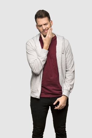 Man with sweatshirt with toothache over grey background