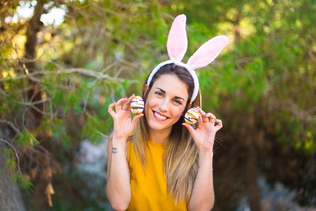 Young woman wearing bunny ears and with colorful Easter egg at outdoors